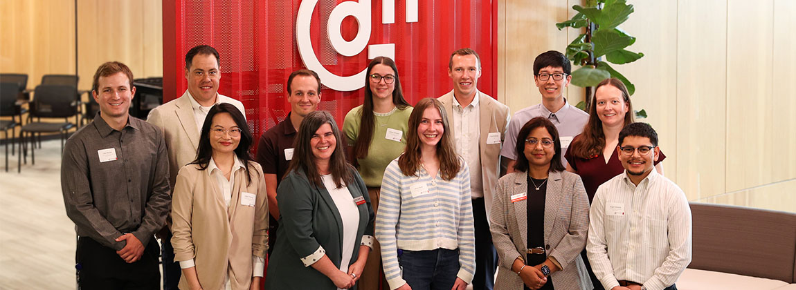 a group of people smiling in front of a red wall